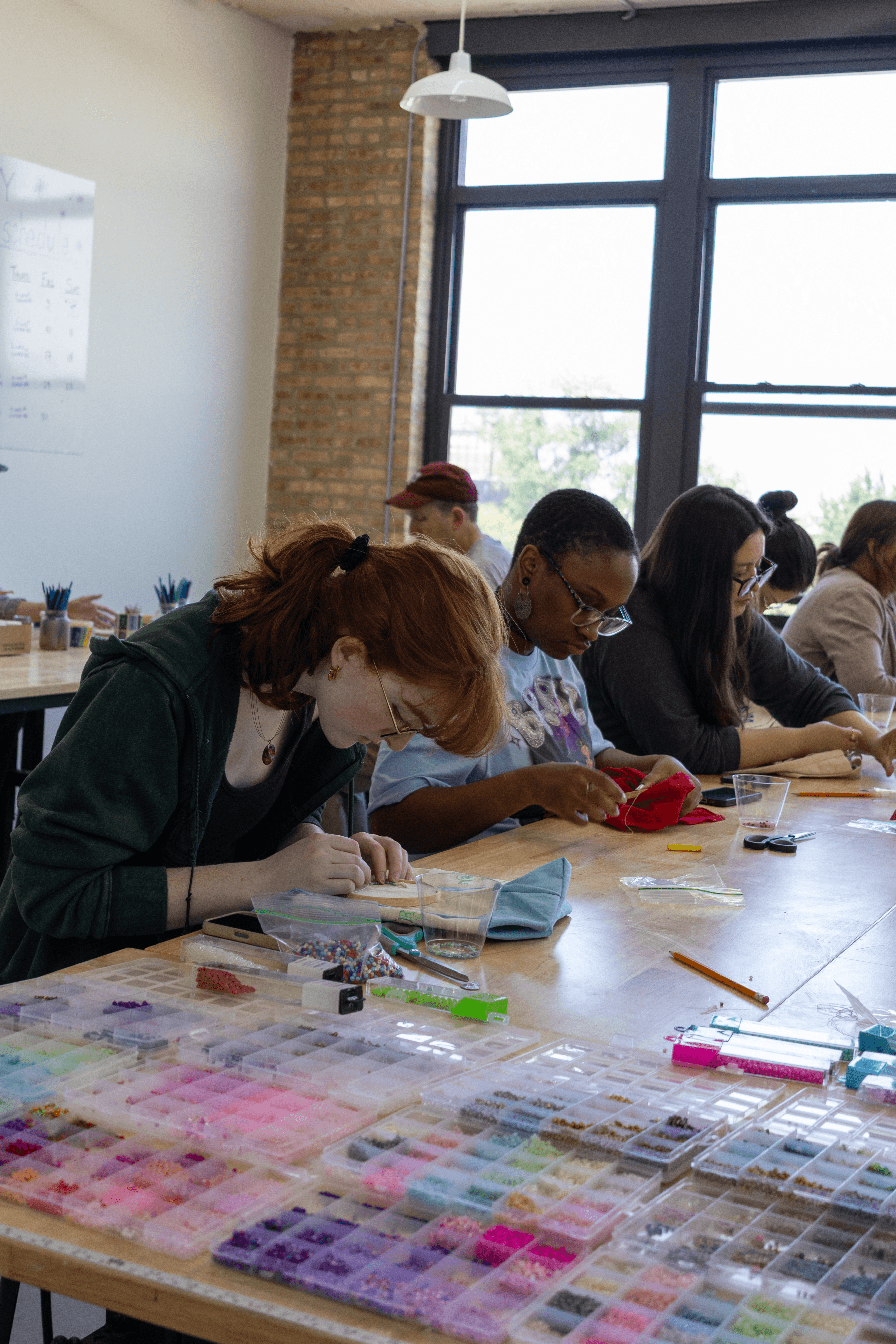Students focused on beading at the studio table