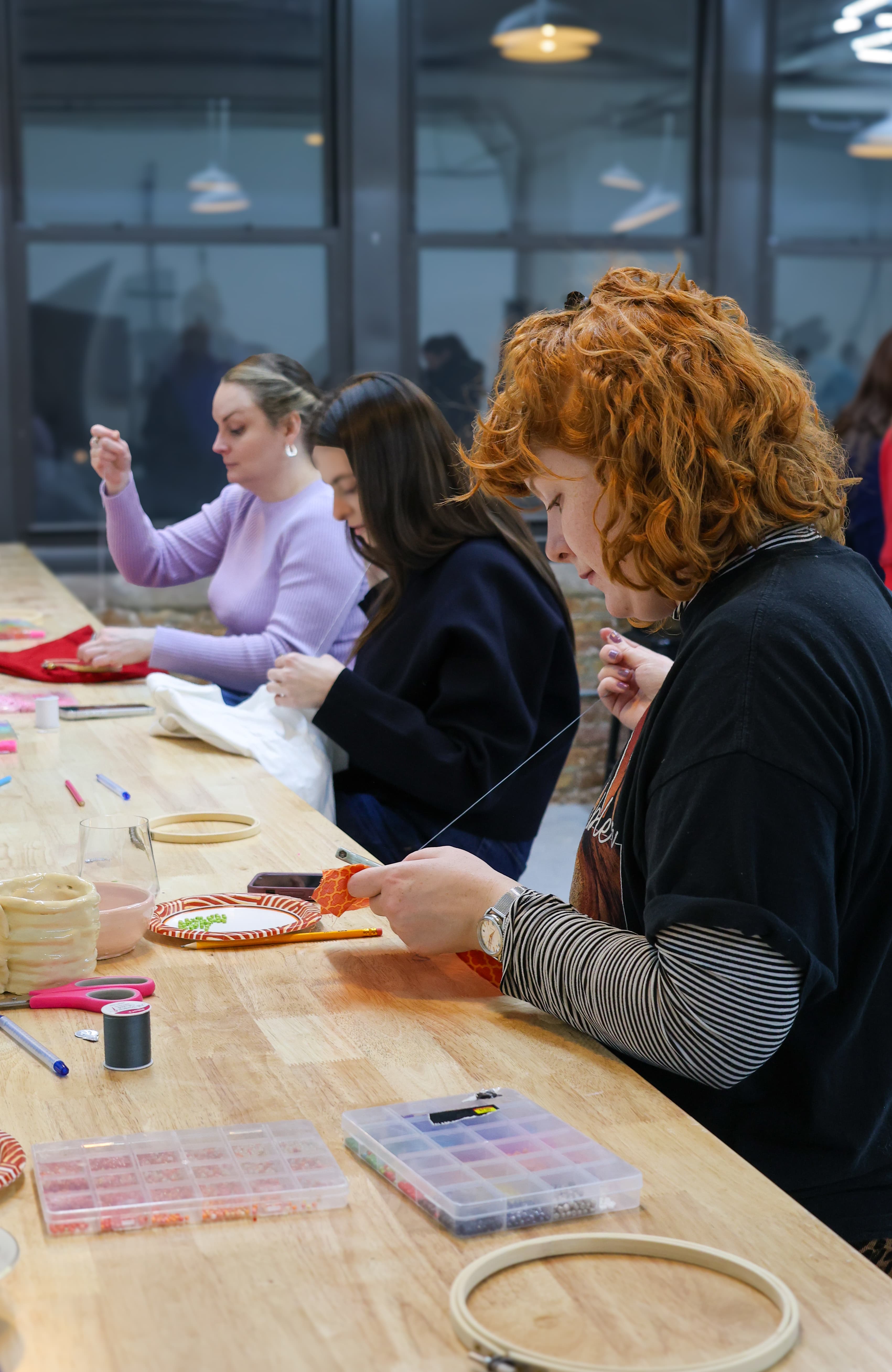 Student threading embroidery needle with focused concentration