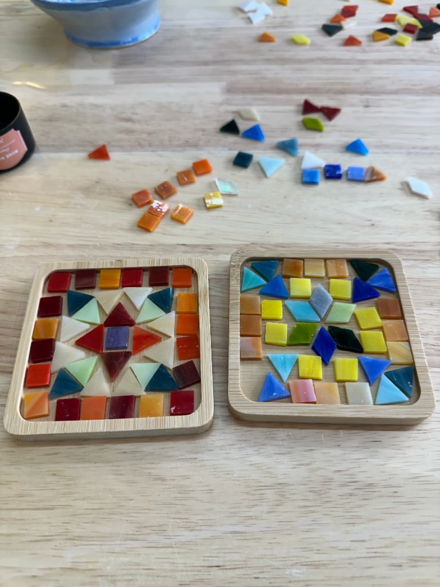 Mosaic coaster designs in progress at the workshop table